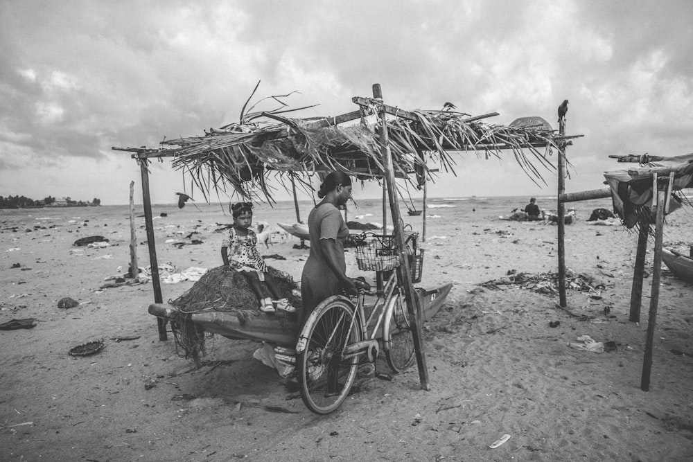 Foto en escala de grises de mujer sentada en silla de playa bajo sombrilla