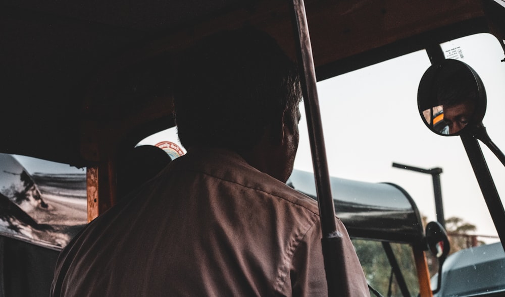man in brown shirt sitting inside car during daytime