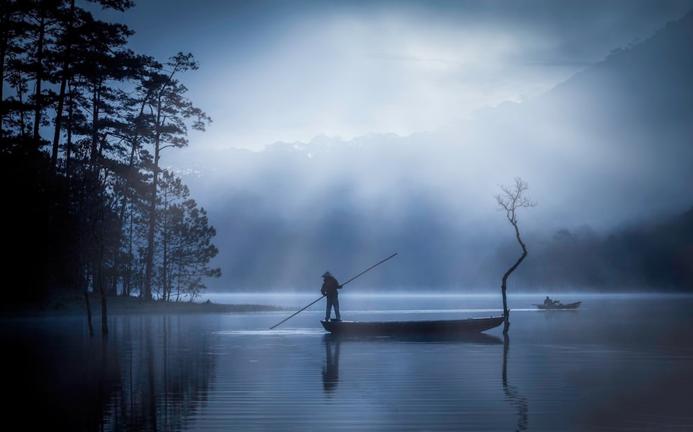 man in black jacket fishing on lake during daytime