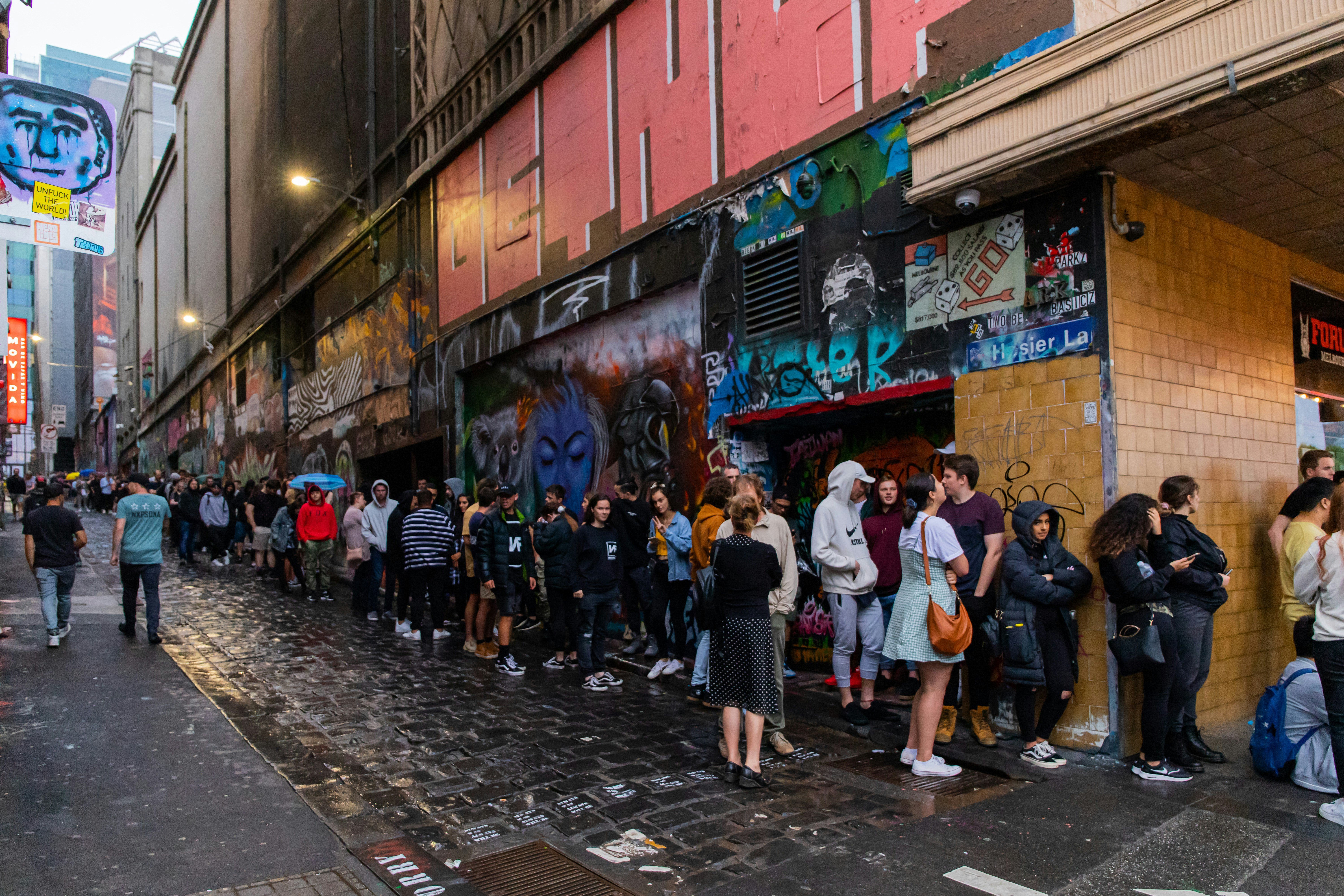 Crowd lined up along a shopfront-lined laneway