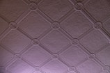 A textured ceiling pattern featuring a grid of interlocking circles and diagonal lines. The surface has a subtle texture, and the pattern is consistent across the entire surface.
