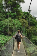 woman in black jacket and black pants standing on hanging bridge