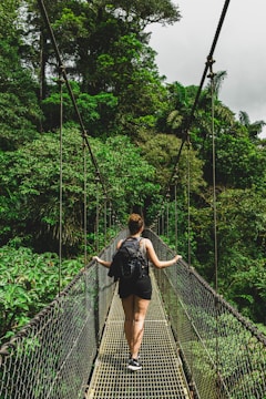 woman in black jacket and black pants standing on hanging bridge