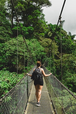 woman in black jacket and black pants standing on hanging bridge