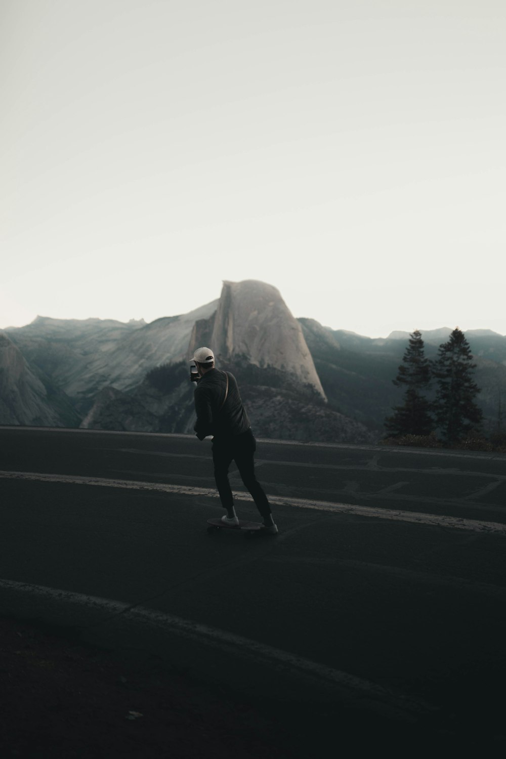 man in black jacket and black pants standing on gray asphalt road during daytime