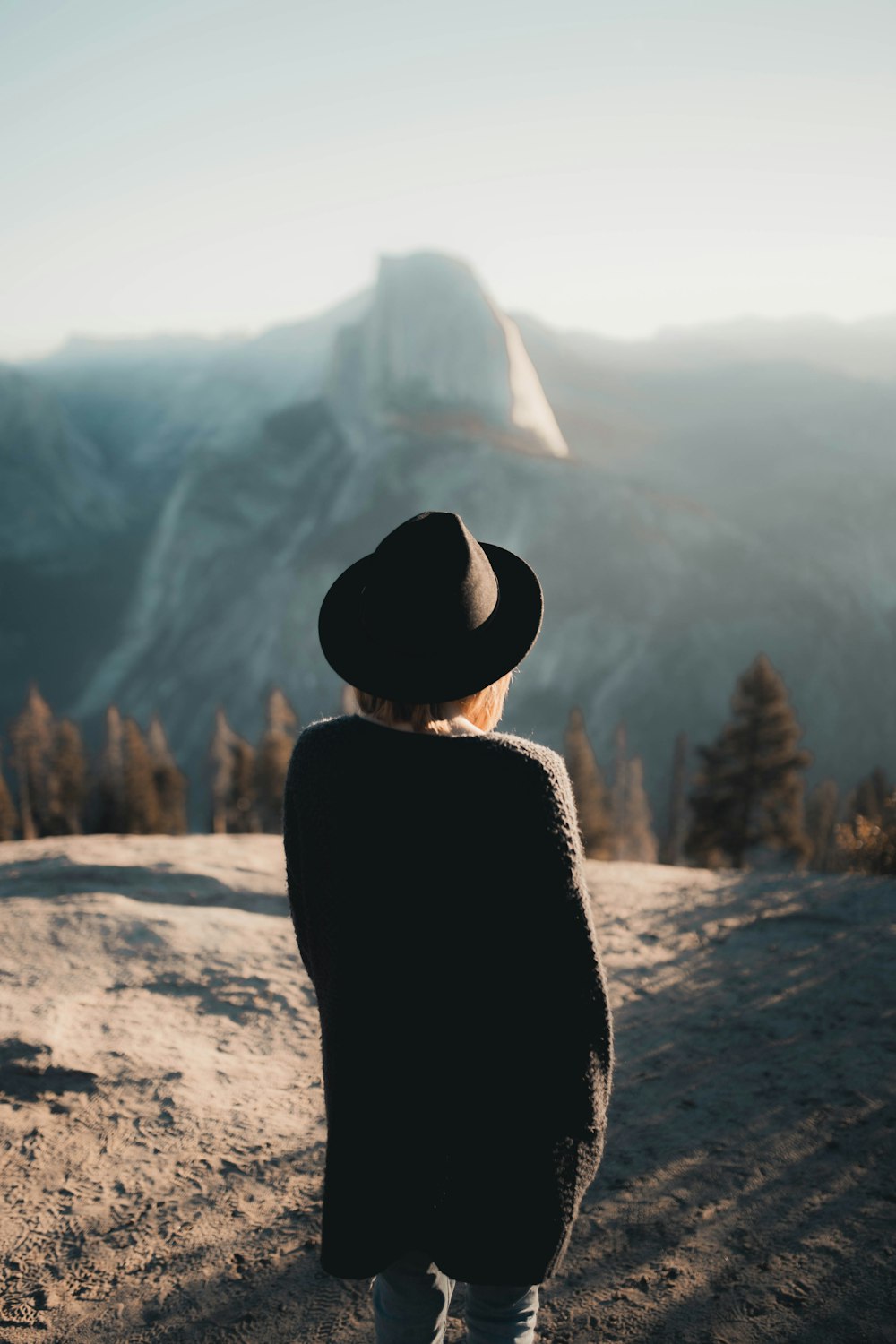 woman in black coat and brown hat standing on brown field during daytime