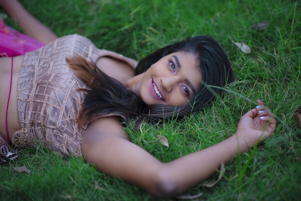 woman in white and brown stripe shirt lying on green grass field