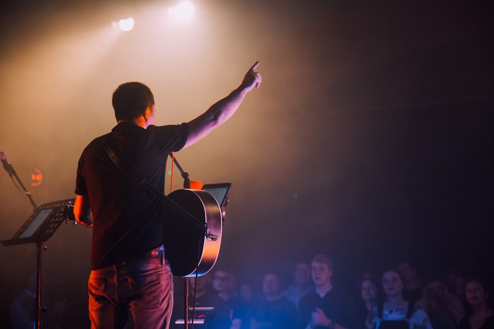 man in black long sleeve shirt and red pants standing on stage