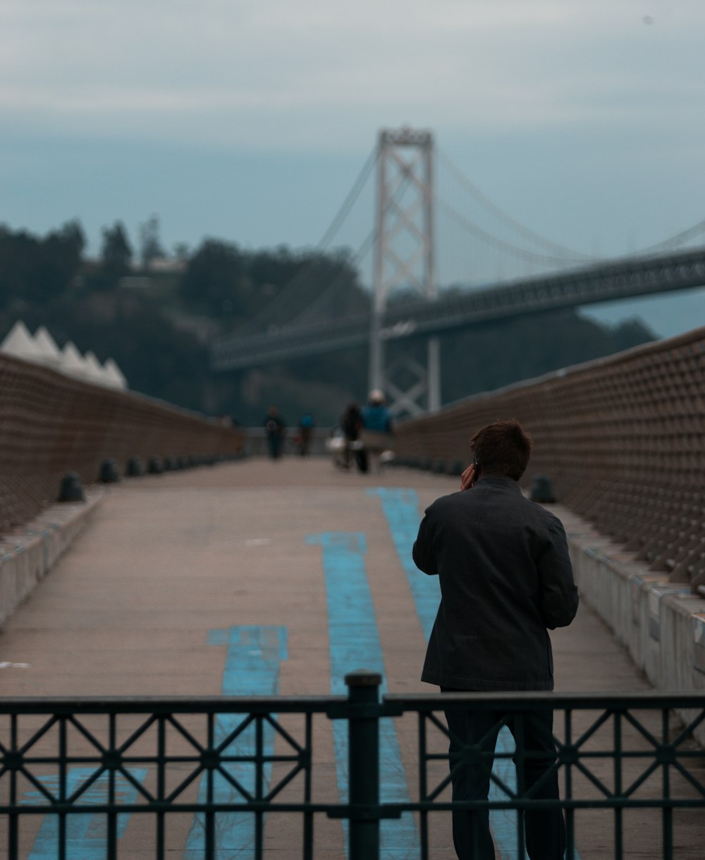 man in black jacket walking on bridge during daytime