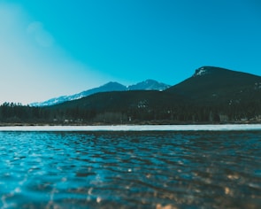 body of water near mountain during daytime