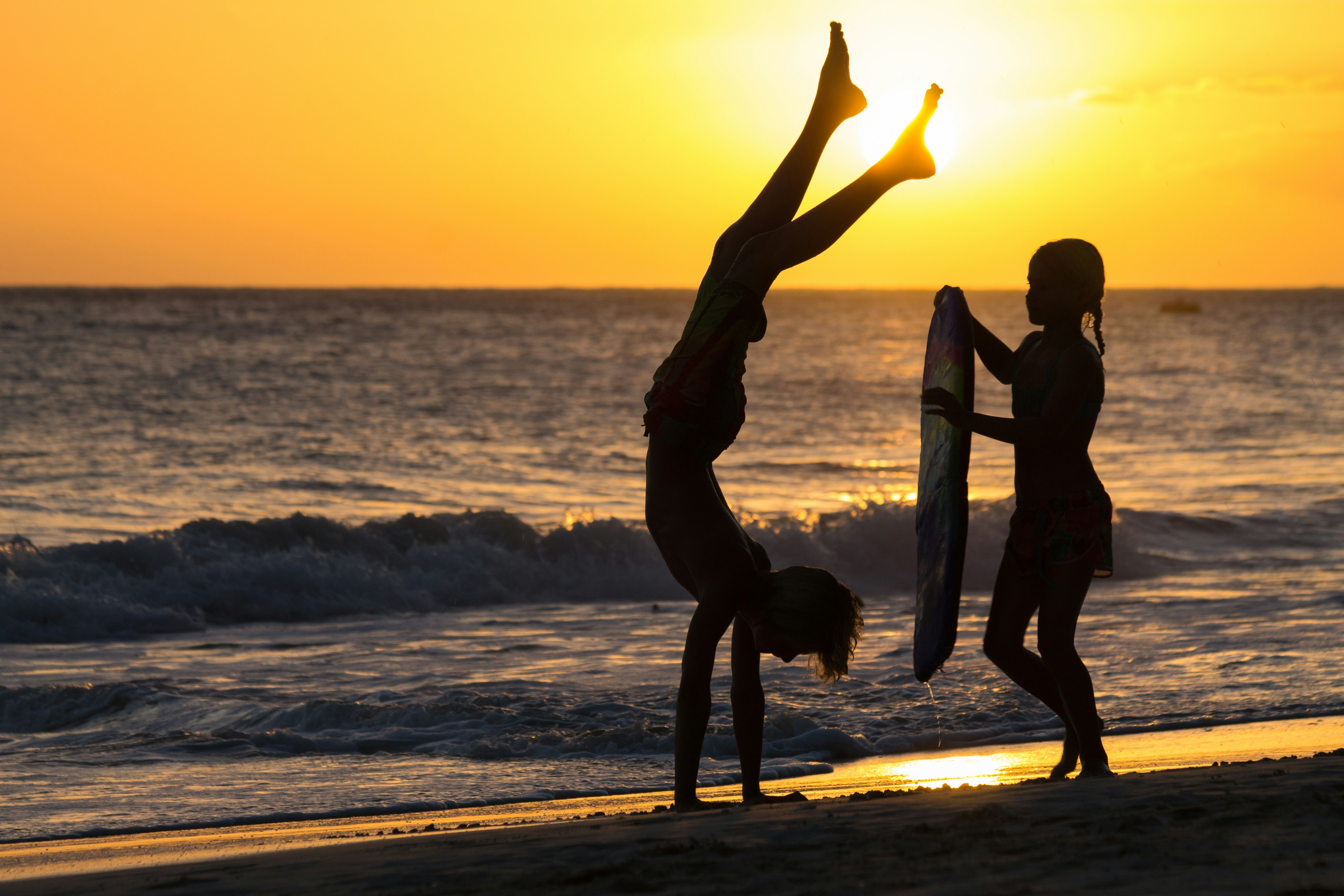 silhouette of 2 women and man standing on beach during sunset barbados teams background