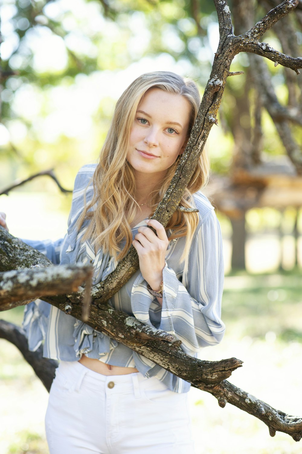 woman in white long sleeve shirt holding brown tree branch