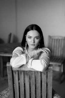 grayscale photo of woman in long sleeve shirt sitting on bench