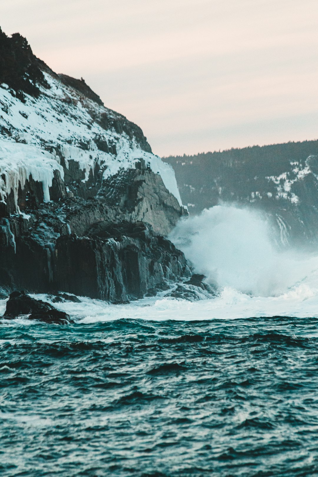 grayscale photo of ocean waves crashing on rocky mountain