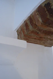 Artisan smoothing plaster on a wall corner in a bright, modern room.