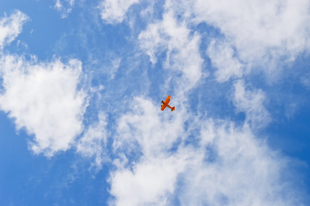 orange and black plane in mid air under blue sky during daytime