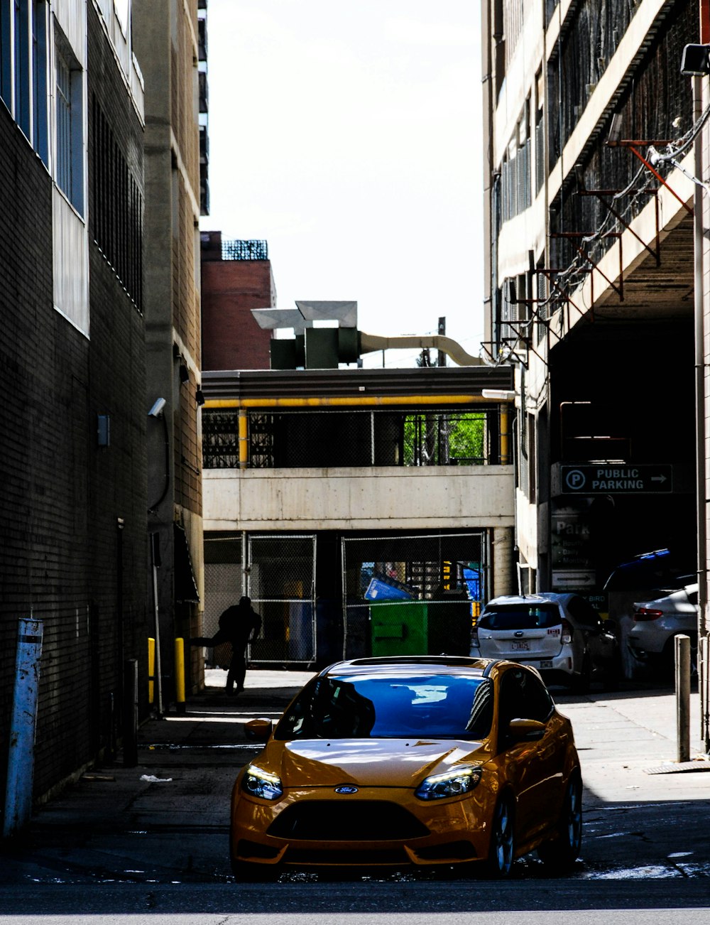 yellow car parked beside brown building during daytime