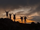 silhouette of people on top of mountain during sunset