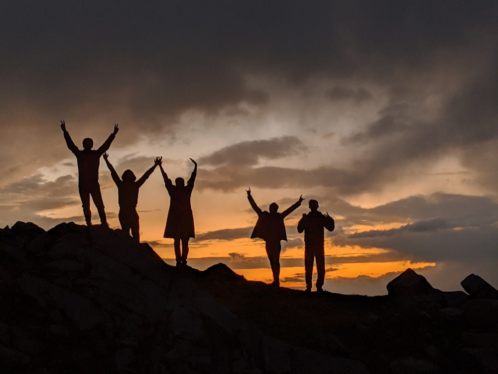 silhouette de personnes au sommet de la montagne pendant le coucher du soleil
