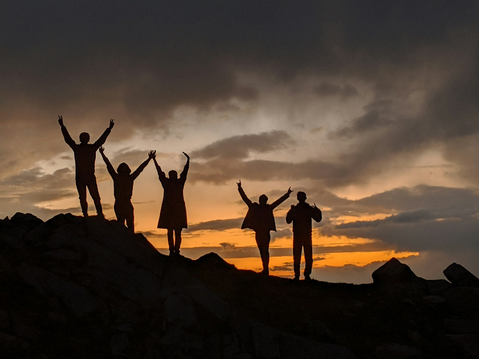 silhouette of people on top of mountain during sunset