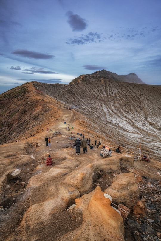 people walking on rocky mountain under blue sky during daytime in Ijen Indonesia