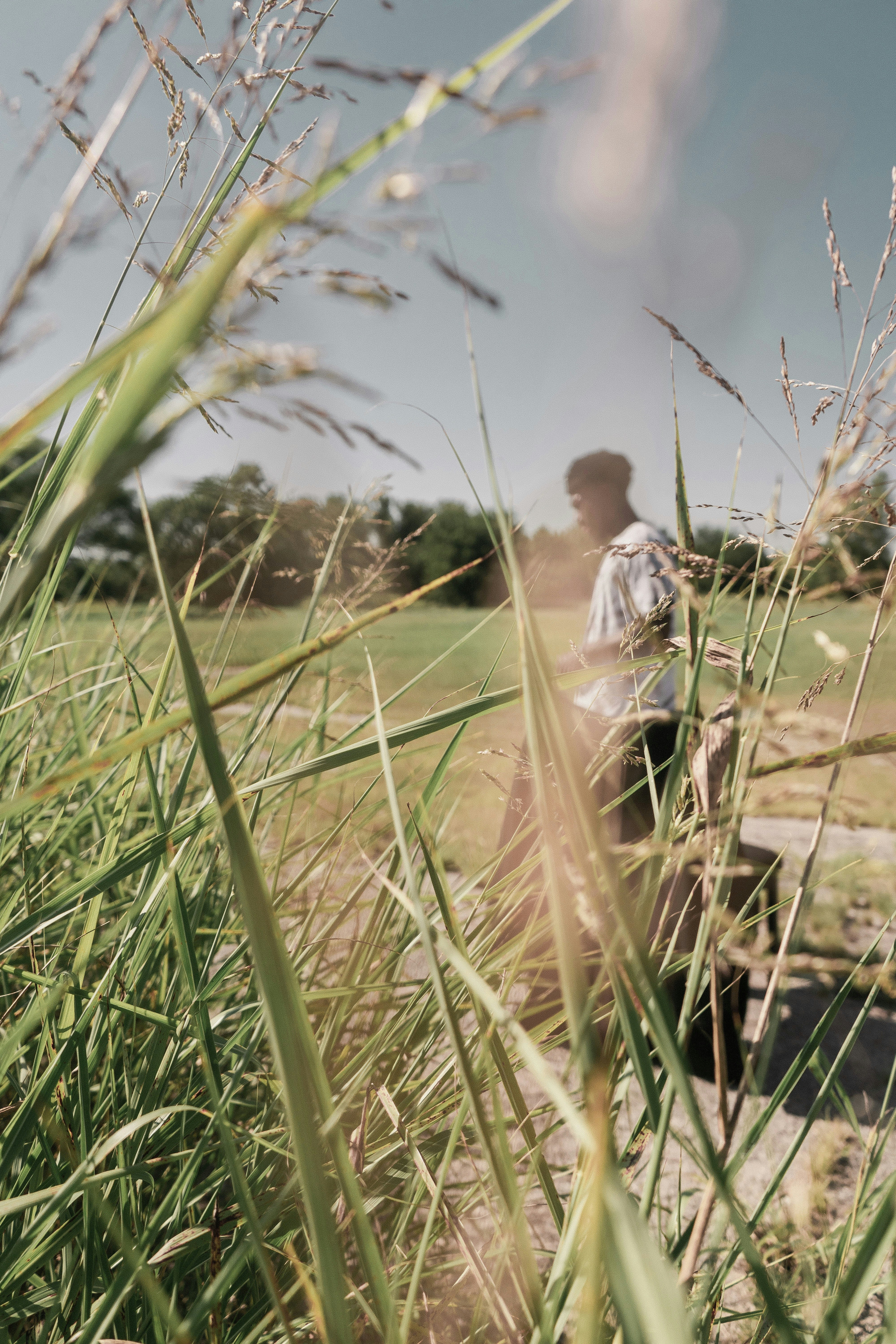 man in white shirt walking on green grass field during daytime