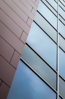 Side-by-side view of a 3D CAD render and the finished aluminum facade on site.