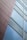 A modern architectural design featuring a close-up view of a building facade with two distinct sections. One side is a textured surface with horizontal linear patterns, and the other side consists of reflective glass panels in a clean, geometric arrangement.