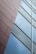A modern architectural design featuring a close-up view of a building facade with two distinct sections. One side is a textured surface with horizontal linear patterns, and the other side consists of reflective glass panels in a clean, geometric arrangement.