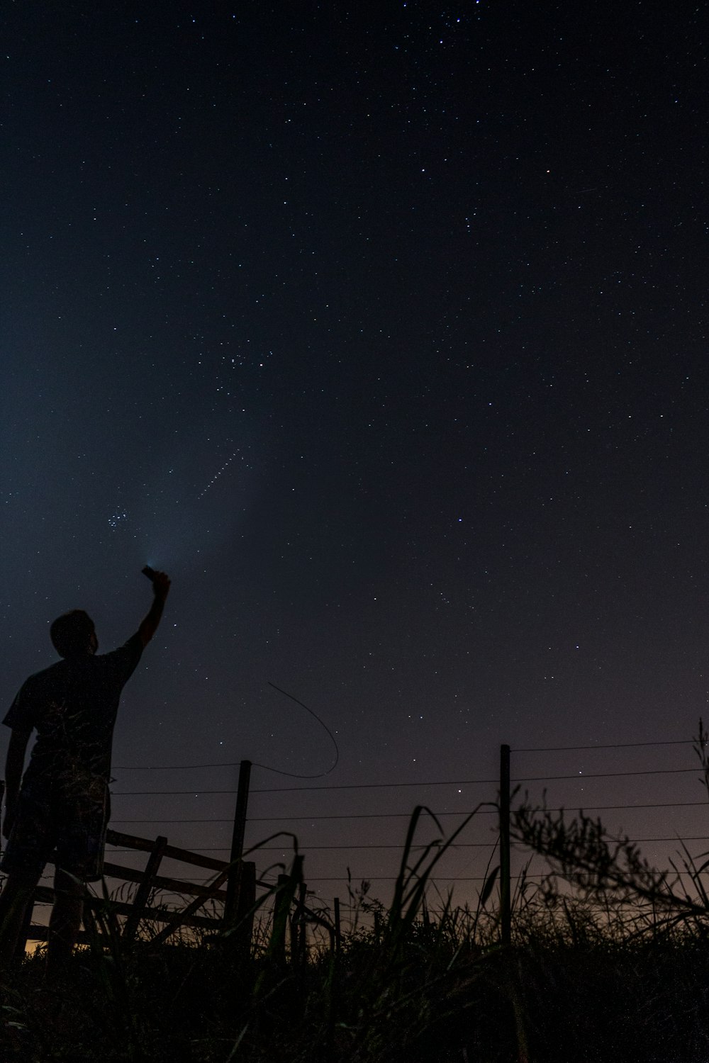 man standing on brown wooden fence under starry night