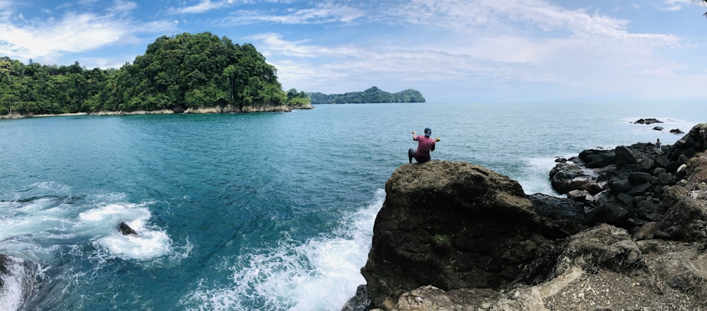 2 person sitting on rock formation near body of water during daytime