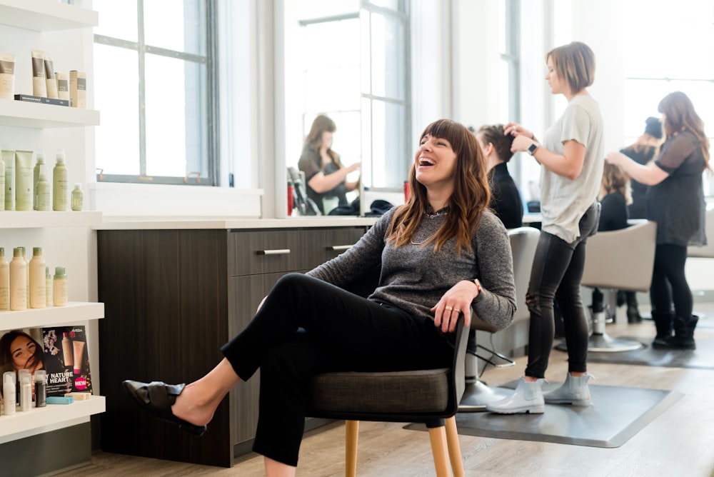 Femme en pull gris assise sur une chaise en bois marron