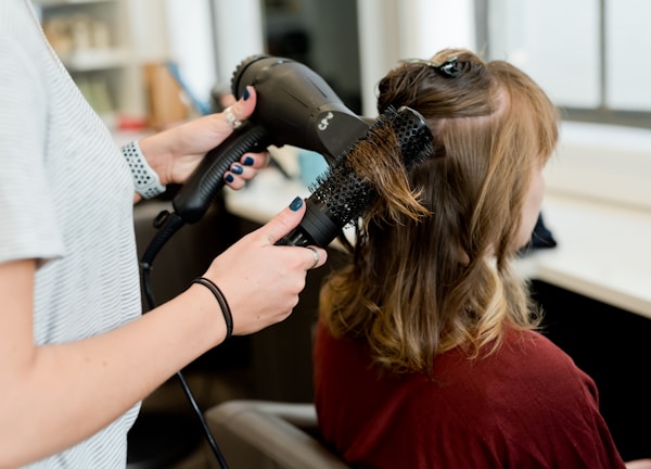 woman in red long sleeve shirt holding hair blower