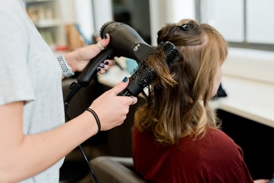 woman in red long sleeve shirt holding hair blower