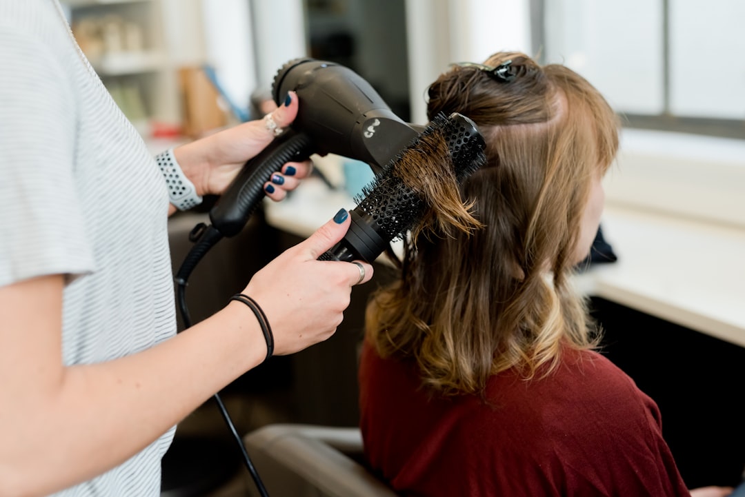  woman in red long sleeve shirt holding hair blower comb