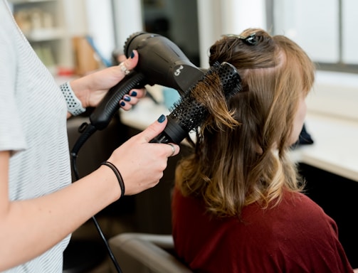 woman in red long sleeve shirt holding hair blower