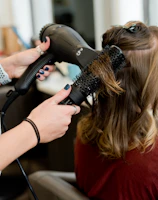 woman in red long sleeve shirt holding hair blower
