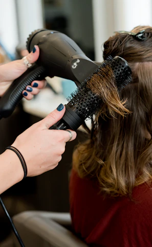 woman in red long sleeve shirt holding hair blower
