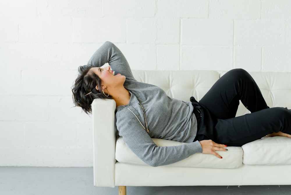 woman in gray long sleeve shirt and black pants sitting on white couch