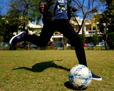 man in blue and white adidas long sleeve shirt and black pants playing soccer during daytime