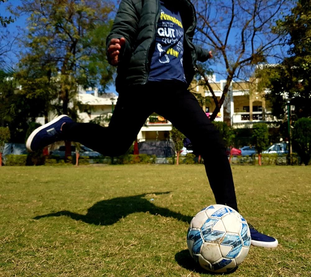 homem em azul e branco adidas camisa de manga comprida e calças pretas jogando futebol durante o dia