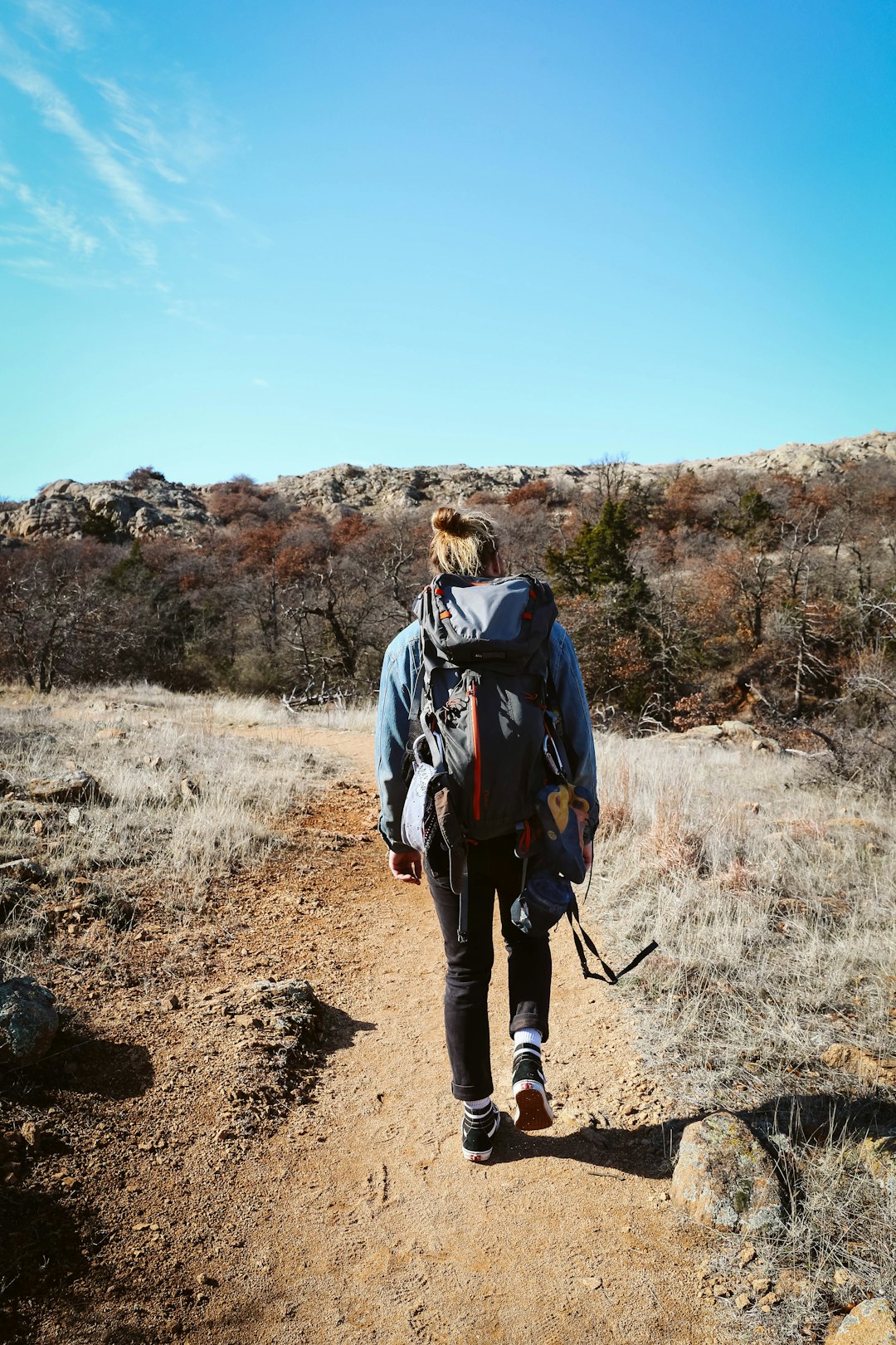 woman in black jacket and black pants walking on dirt road during daytime