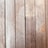 Wooden planks aligned vertically, featuring a natural wood grain and small evenly spaced screws securing them in place. The texture and color of the wood suggest aging, with slight wear and discoloration visible on the surface.