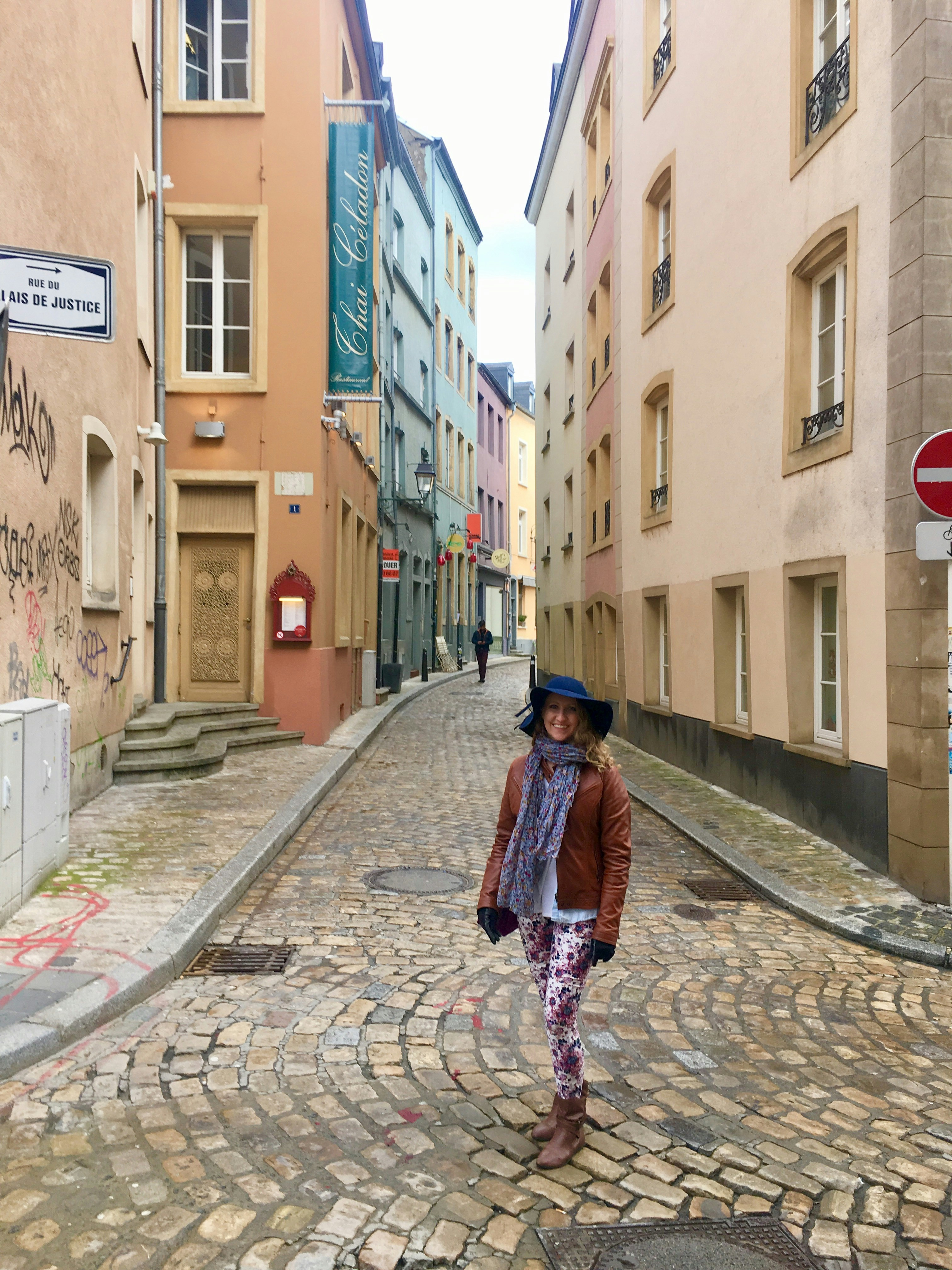woman in red and black plaid coat walking on sidewalk during daytime