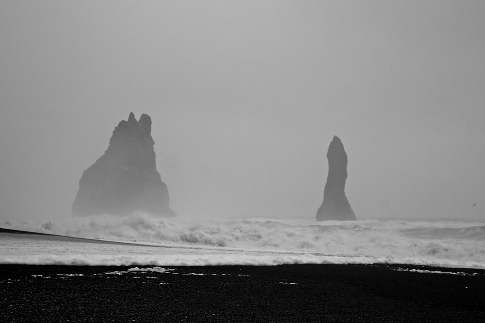 grayscale photo of rock formation on sea