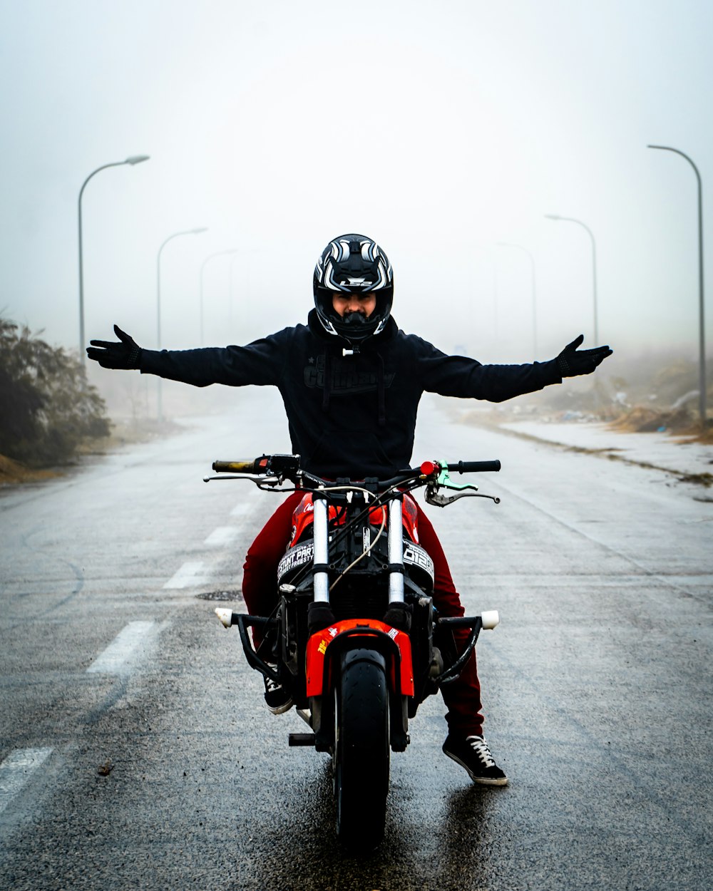 man in black helmet riding red motorcycle on road during daytime