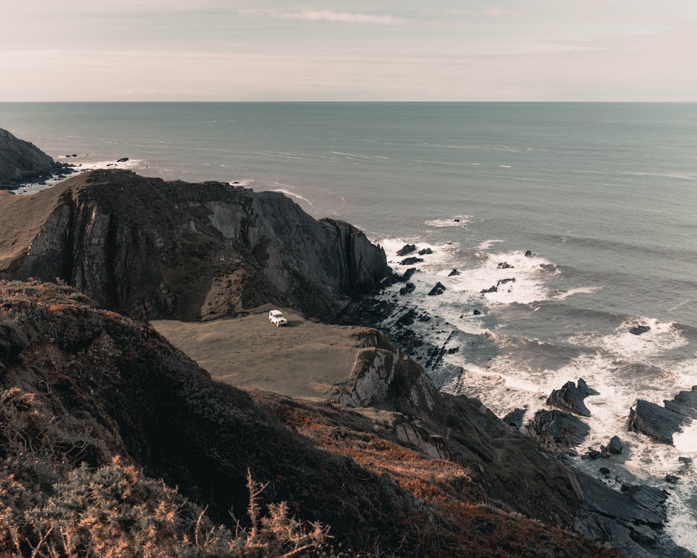 montanha rochosa marrom ao lado do mar durante o dia