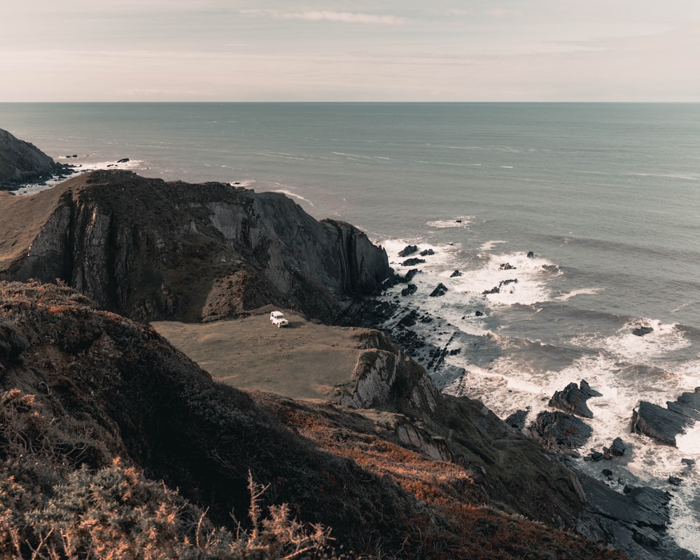 brown rocky mountain beside sea during daytime