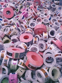 A collection of colorful tickets or coupons rolled into cylinders, with various denominations and text visible on each roll. The tickets are stacked in a chaotic and overlapping manner, showcasing a range of colors and patterns.