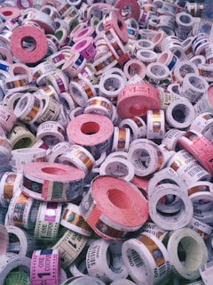A collection of colorful tickets or coupons rolled into cylinders, with various denominations and text visible on each roll. The tickets are stacked in a chaotic and overlapping manner, showcasing a range of colors and patterns.